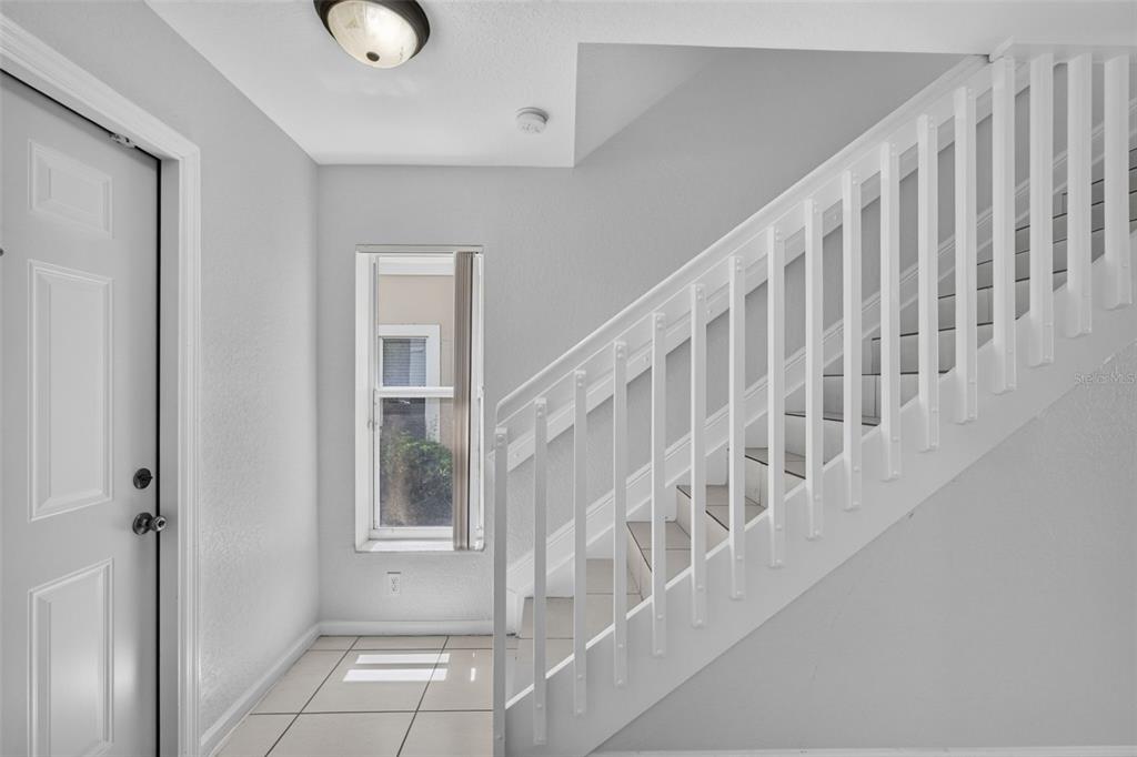 An entryway features white tile flooring, a white front door, and a staircase with railings — 946 SUMMIT LAKE DRIVE, WEST PALM BEACH, FL