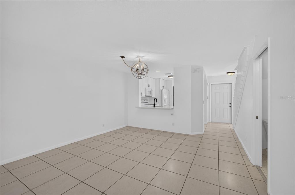 An open-concept dining area features light-colored tile flooring, a modern chandelier, and a kitchen pass-through — 946 SUMMIT LAKE DRIVE, WEST PALM BEACH, FL