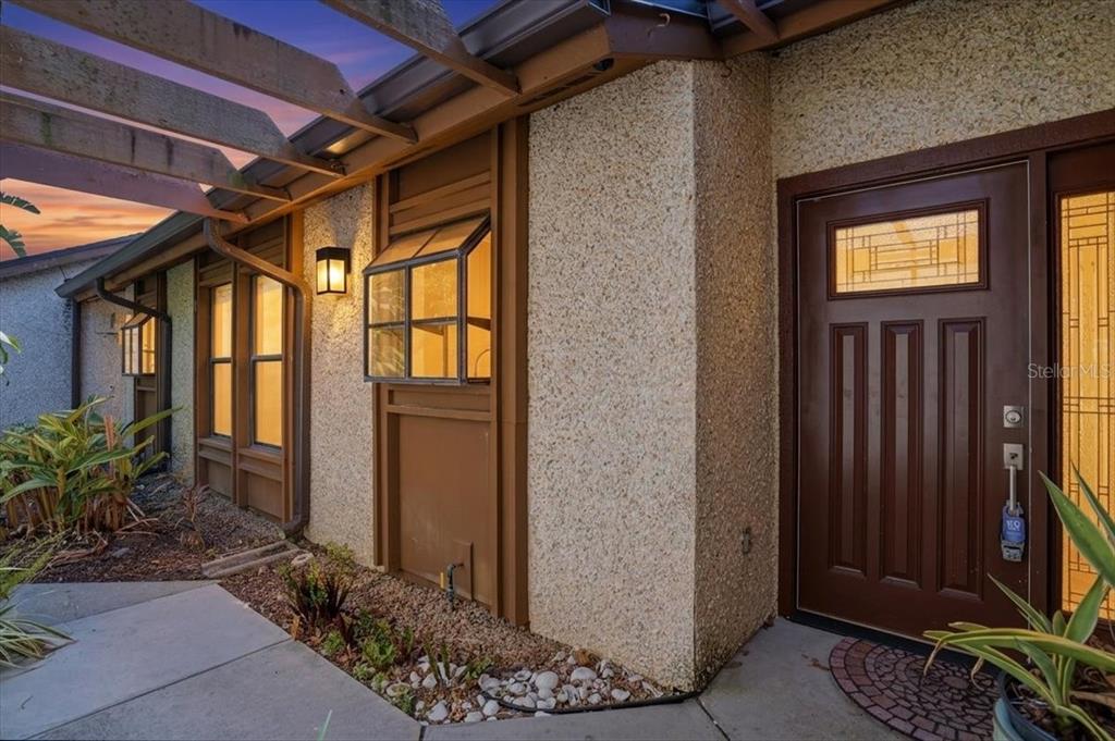 A brown front door with a glass insert sits beside a window with a greenhouse extension — 7522 4TH AVENUE W, BRADENTON, FL