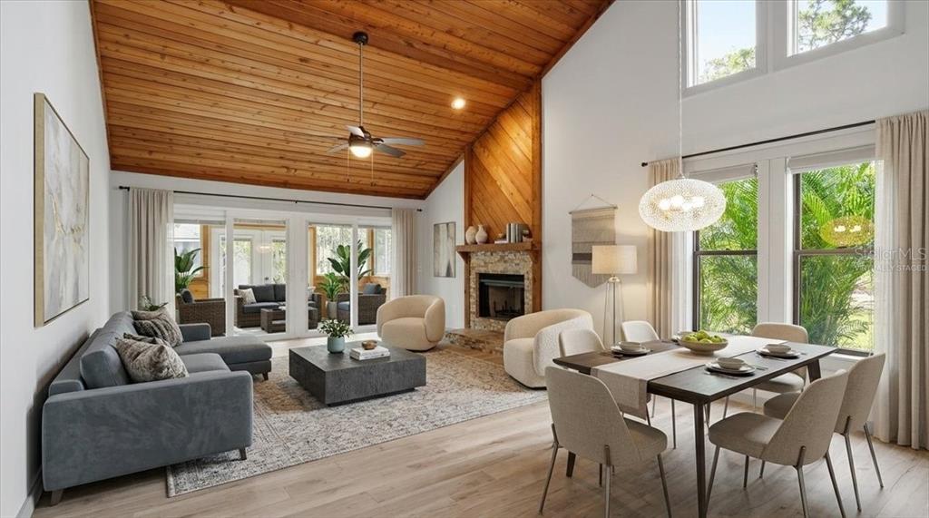 An open-concept living and dining area features a vaulted wood ceiling and stone fireplace — 7522 4TH AVENUE W, BRADENTON, FL