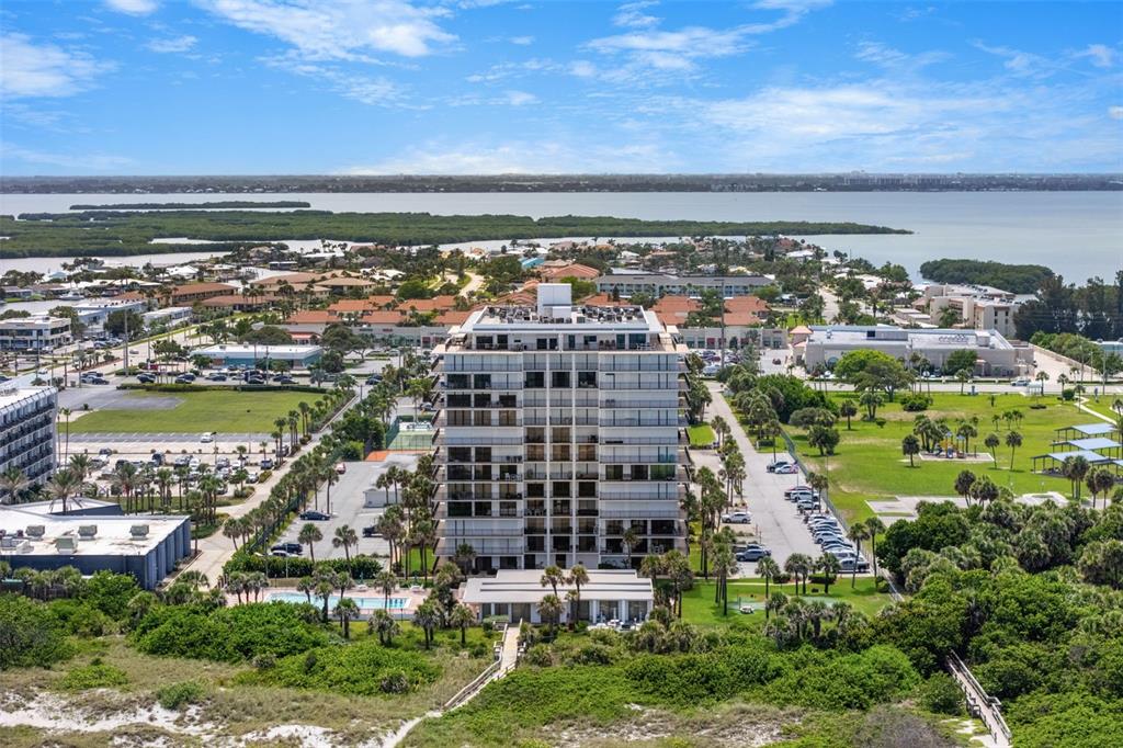 An aerial view of a multi-story residential building surrounded by parking, greenery, and water — 2100 N ATLANTIC AVENUE UNIT 502, COCOA BEACH, FL