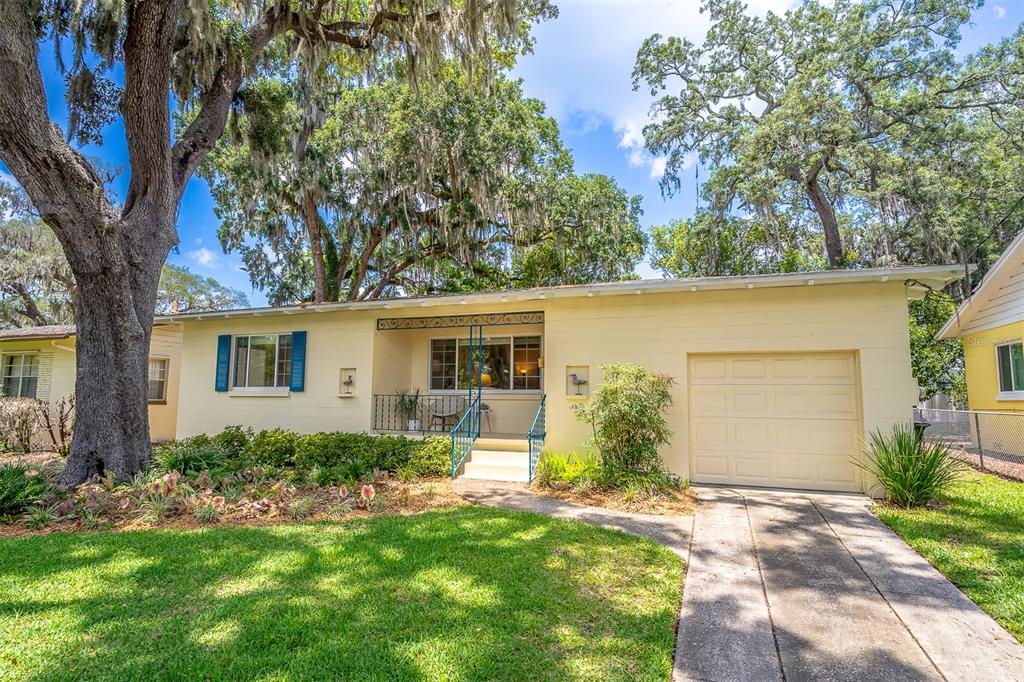 A single-story yellow house with a front porch, attached garage, and large oak trees — 709 LAKE HIGHLAND DRIVE, ORLANDO, FL