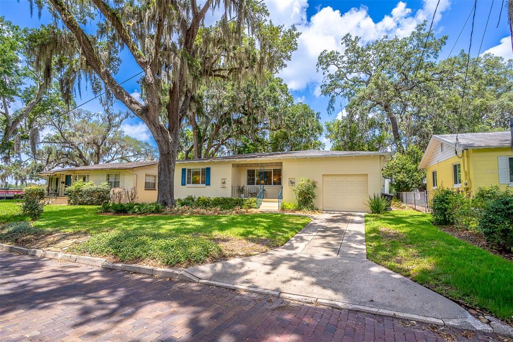 A single-story yellow house with a garage and large oak trees in the front yard — 709 LAKE HIGHLAND DRIVE, ORLANDO, FL