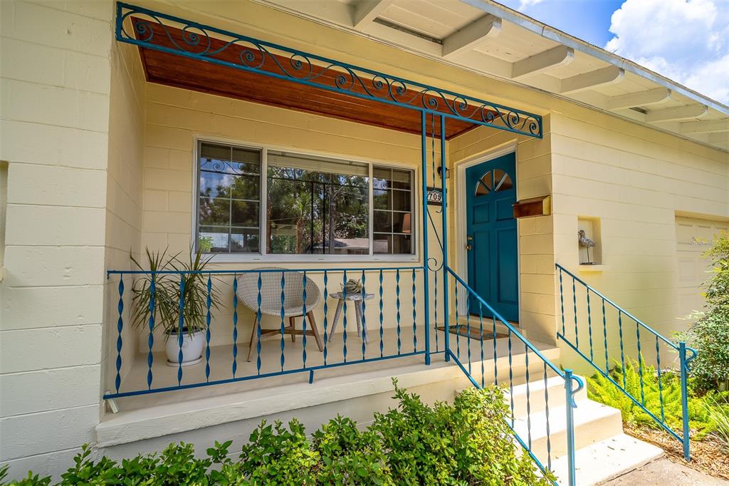 A yellow house exterior features a blue front door, matching railings, and a covered porch — 709 LAKE HIGHLAND DRIVE, ORLANDO, FL