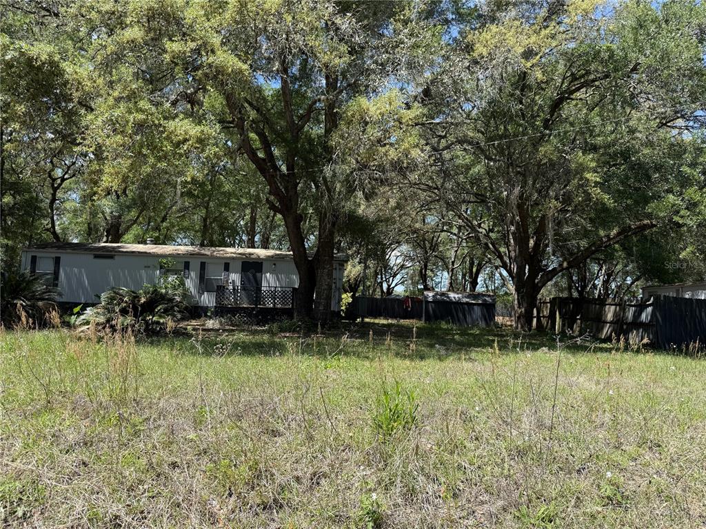 A single-story mobile home sits on a grassy lot shaded by several large trees — 11965/11969 SW 147TH PLACE, DUNNELLON, FL