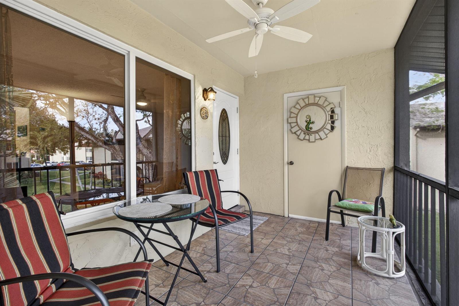 A screened-in patio features tiled flooring, a ceiling fan, outdoor furniture, and two doors — 301 Pine Ridge Circle # 2, FL 33463, FL
