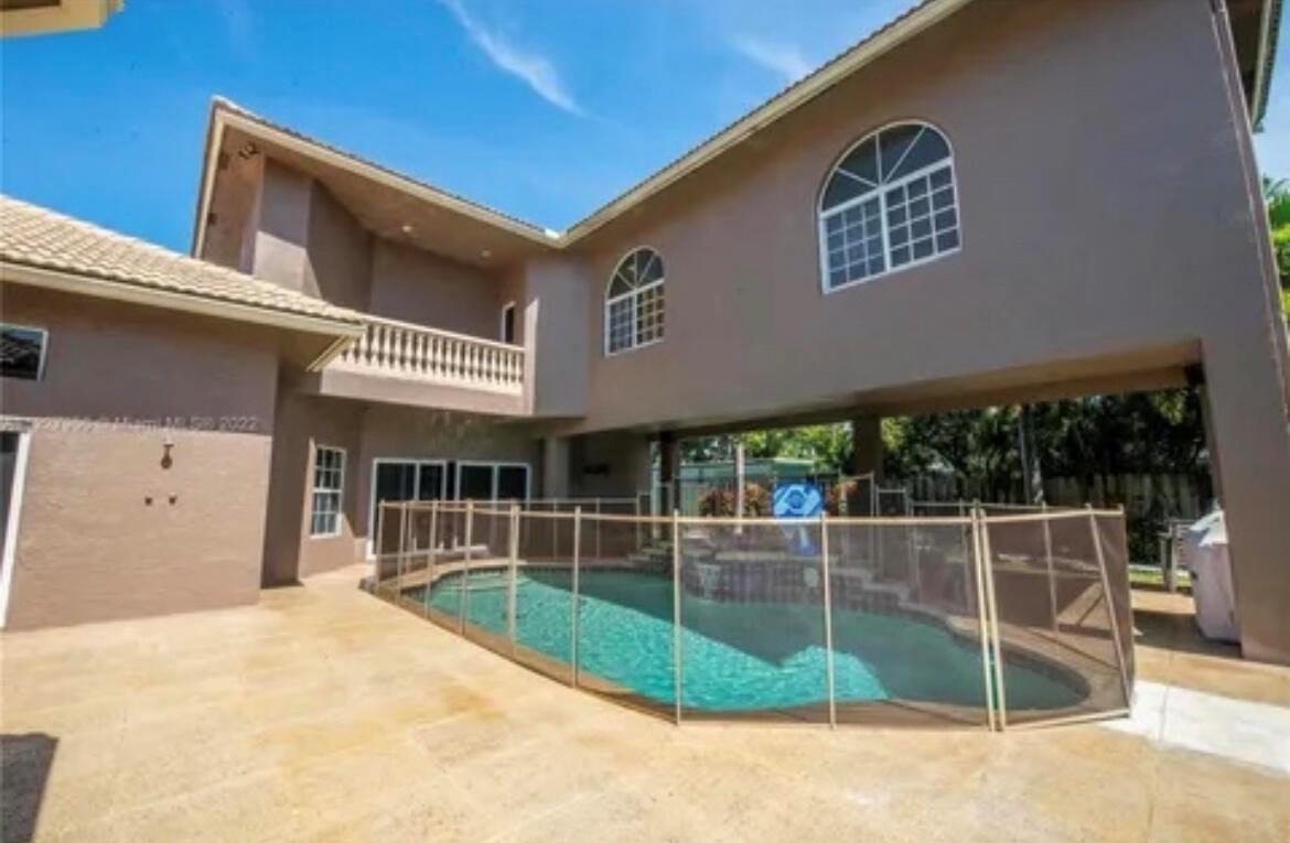 A two-story house exterior features a swimming pool enclosed by a mesh safety fence — 423 NE 3rd Street, Pompano Beach FL 33060, POMPANO BEACH, FL