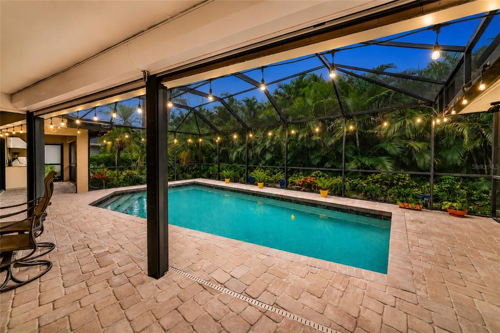 A screened-in patio features a rectangular swimming pool surrounded by brick pavers and lush landscaping — 486 YACHT HARBOR DRIVE, OSPREY, FL