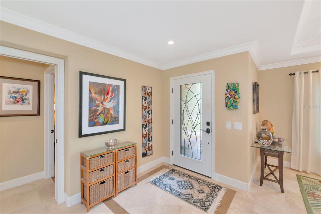 An entryway features a glass-paneled front door, tile flooring, a wicker console, and wall art — 486 YACHT HARBOR DRIVE, OSPREY, FL