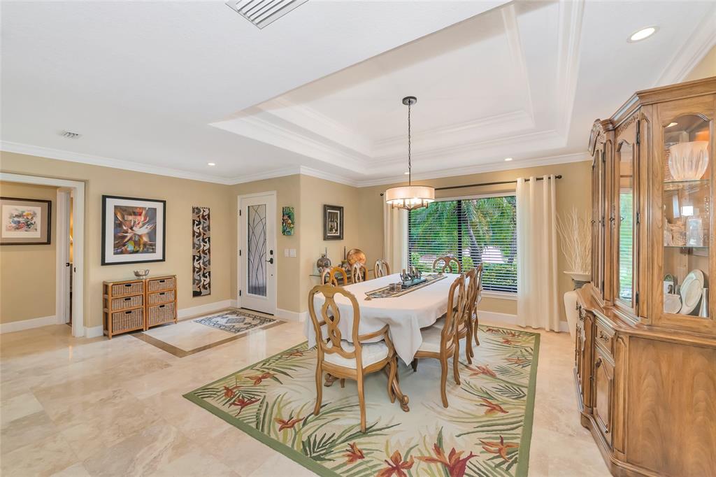 A dining room features a tray ceiling, tile flooring, a floral rug, and a wooden hutch — 486 YACHT HARBOR DRIVE, OSPREY, FL