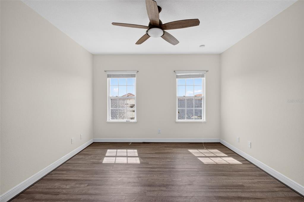 An empty bedroom features wood-look flooring, a ceiling fan, and two windows with blinds — 817 LOBELIA DRIVE, LAKE MARY, FL