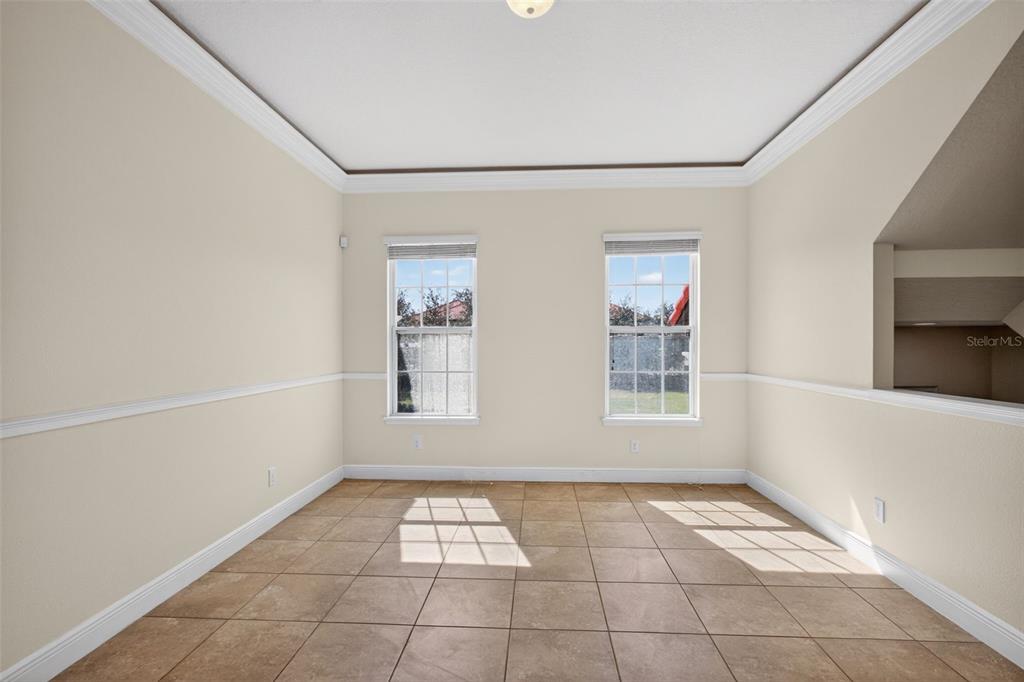An empty room with beige walls, chair rail molding, tile flooring, and two windows — 817 LOBELIA DRIVE, LAKE MARY, FL