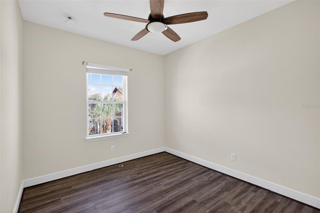 An empty bedroom features wood-look flooring, a ceiling fan, and a window with exterior views — 817 LOBELIA DRIVE, LAKE MARY, FL