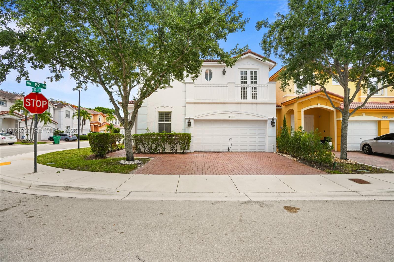 A two-story white house with a brick driveway and a balcony stands on a corner — 8741 NW 110th Ave, Doral FL 33178, DORAL, FL