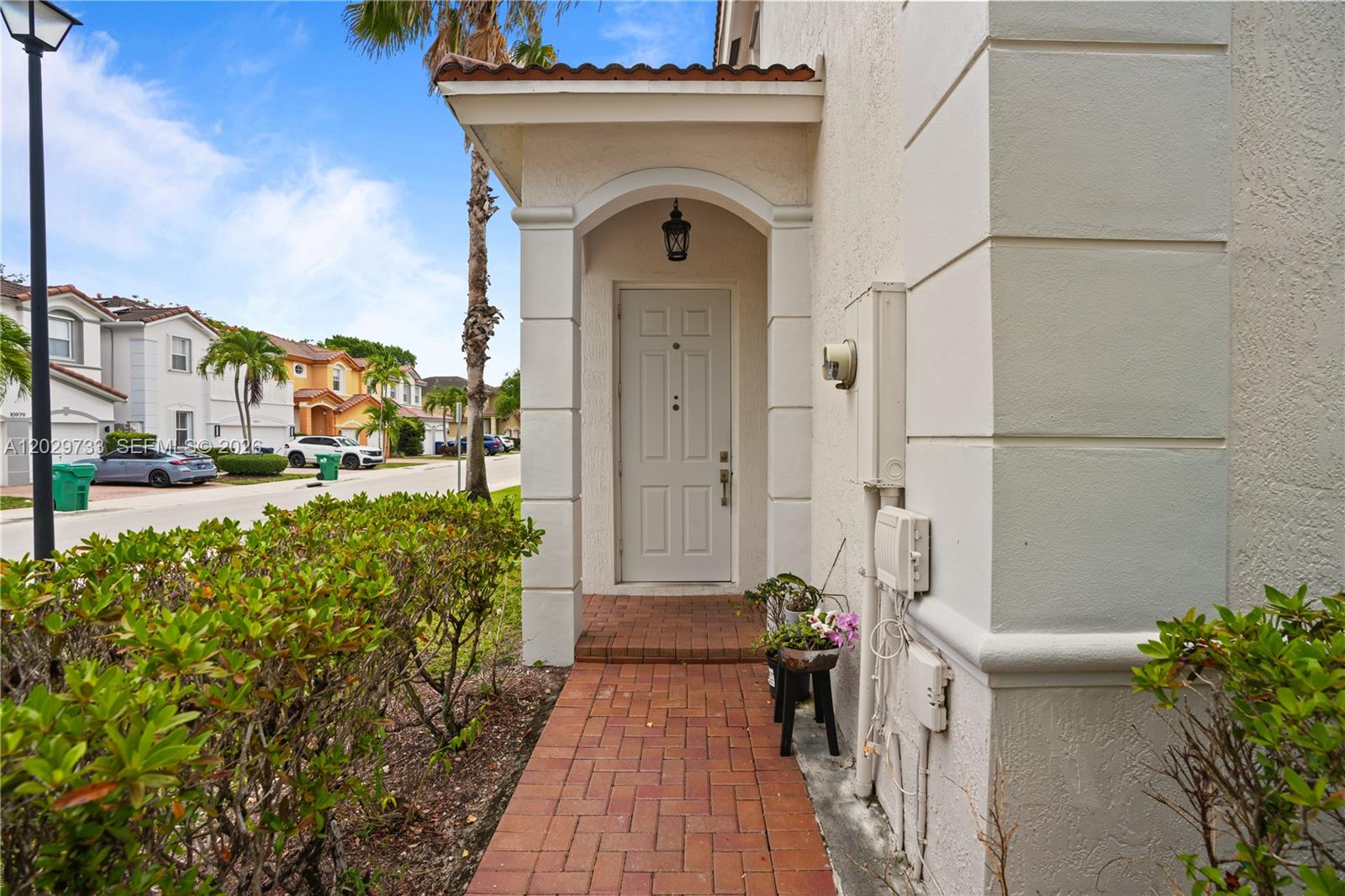 A white front door is recessed under a covered entryway with a brick walkway — 8741 NW 110th Ave, Doral FL 33178, DORAL, FL