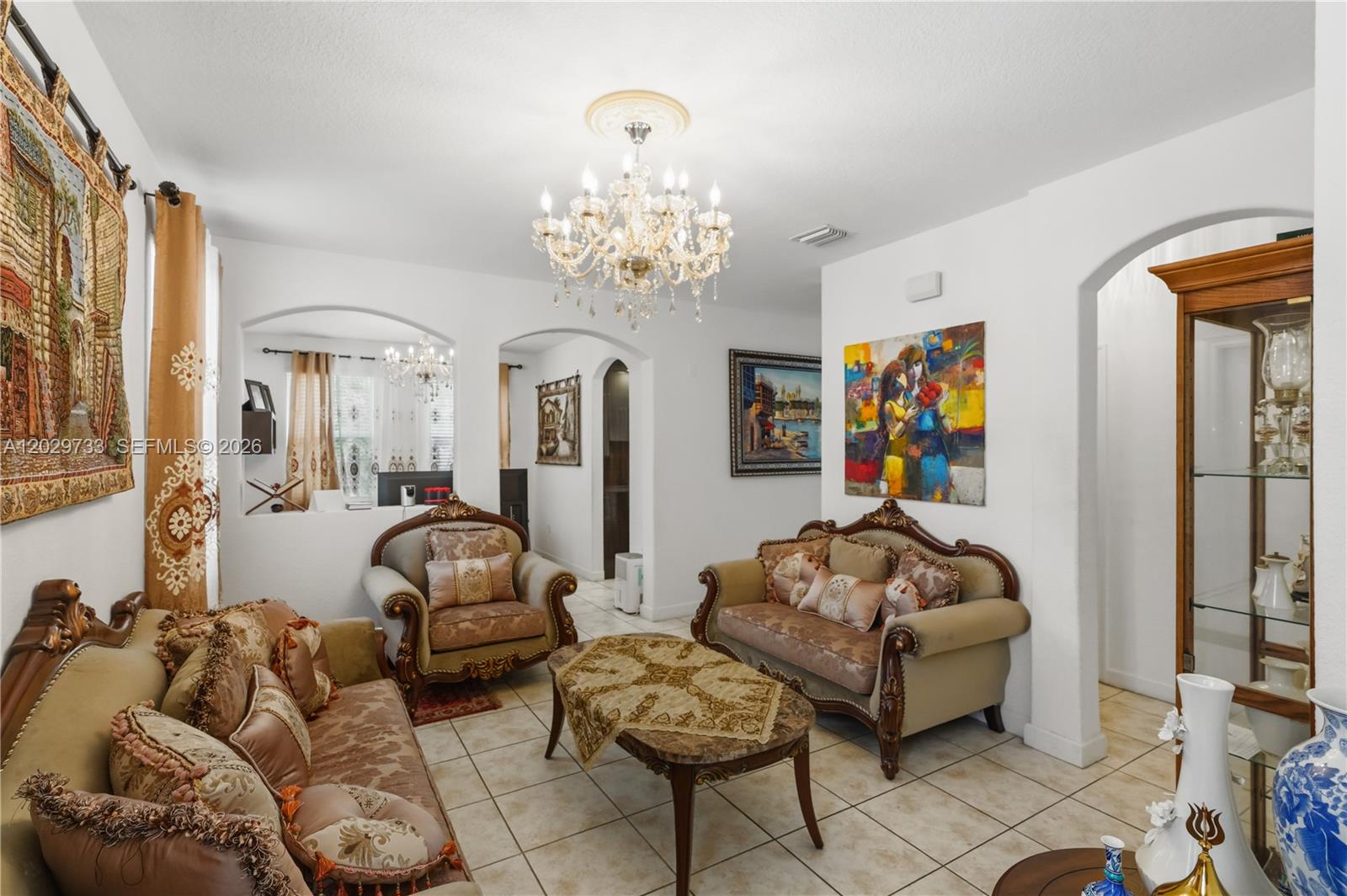 A living room features ornate traditional furniture, a crystal chandelier, and tiled flooring — 8741 NW 110th Ave, Doral FL 33178, DORAL, FL