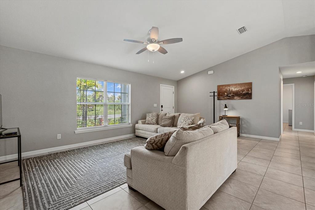 A living room features light gray walls, tile flooring, a ceiling fan, and two beige sofas — 11481 WILLMINGTON BOULEVARD, PORT CHARLOTTE, FL