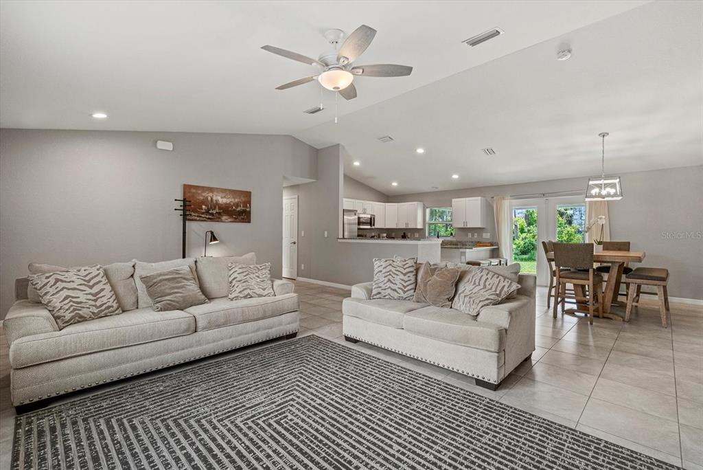 An open-concept living room with two sofas, a patterned rug, and an adjacent dining area — 11481 WILLMINGTON BOULEVARD, PORT CHARLOTTE, FL