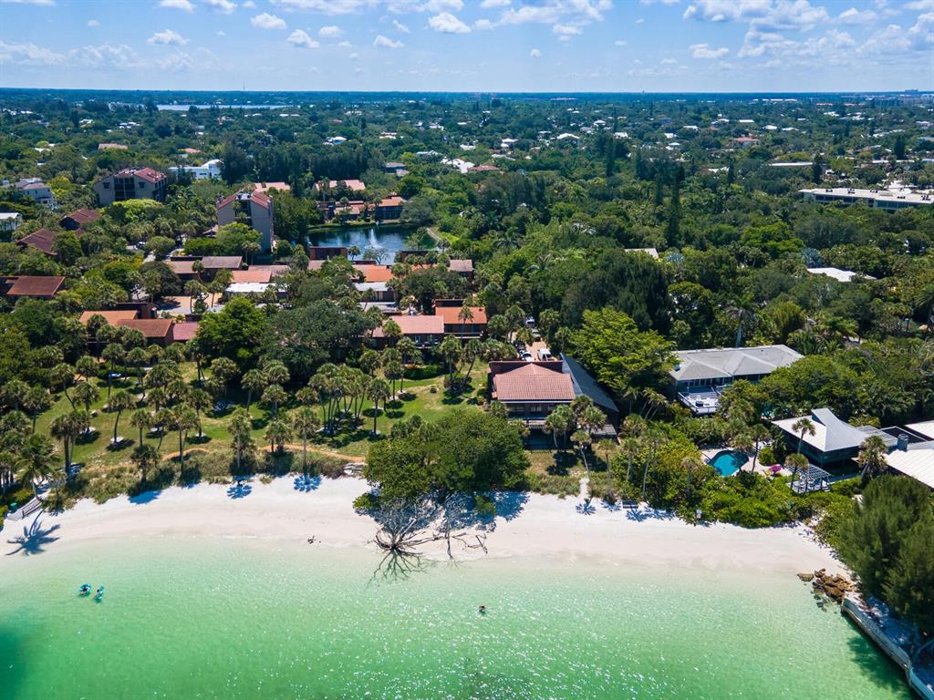 An aerial view of a coastal property featuring a sandy beach, turquoise water, and buildings — 22 SANDY COVE ROAD APT 203, SARASOTA, FL