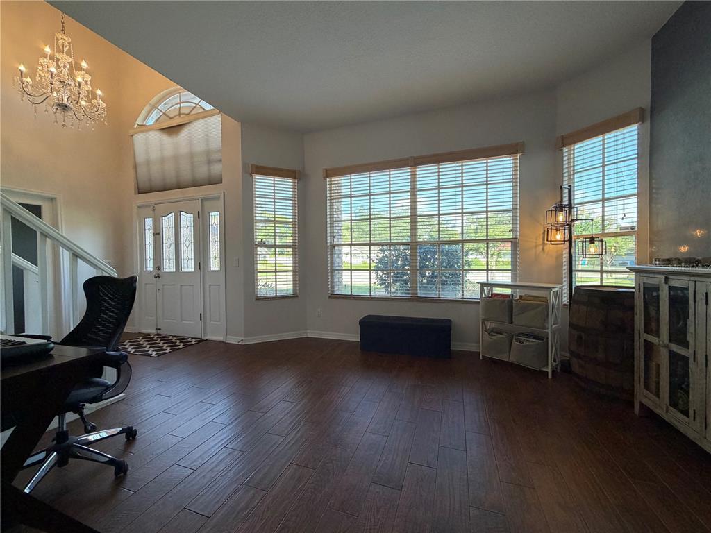 A bright home office with wood-look tile floors, large windows, and a crystal chandelier — 313 MACARTHUR PLACE, MAITLAND, FL