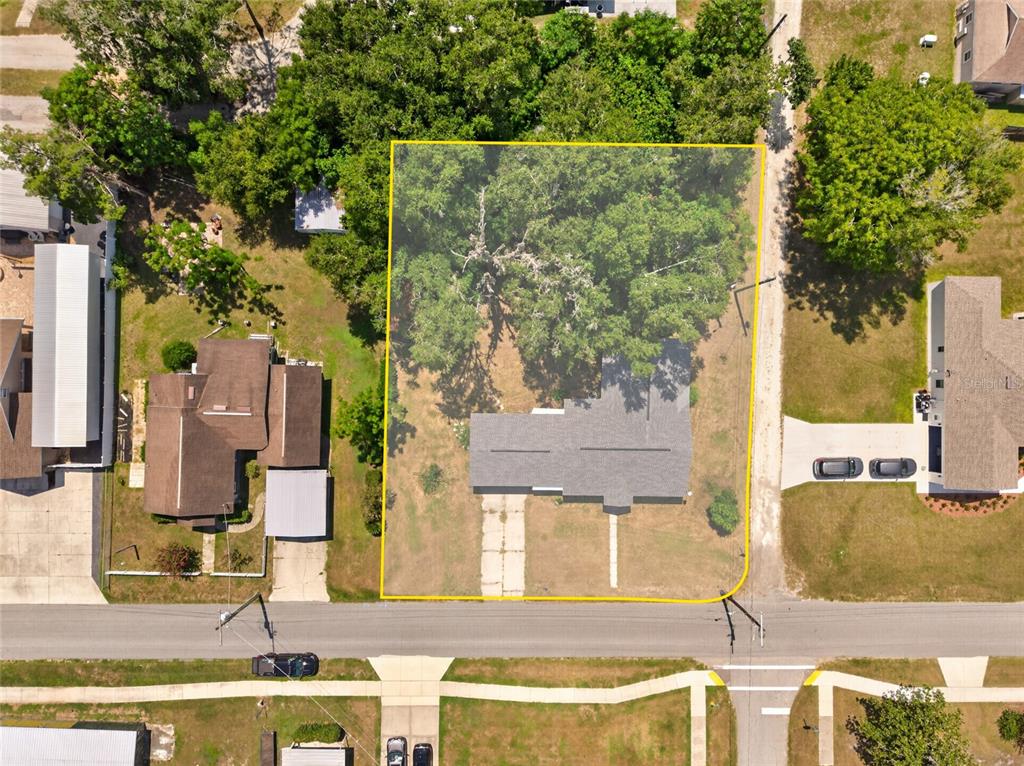 A single-story white house with a carport and a front walkway sits on a lawn — 13725 10TH STREET, DADE CITY, FL