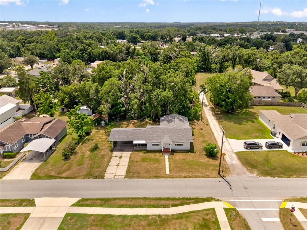 An aerial view shows a single-story house with a carport and driveway on a grassy lot — 13725 10TH STREET, DADE CITY, FL