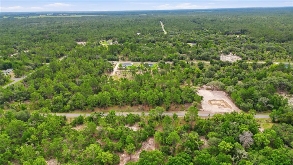 An aerial view shows a wooded lot with a cleared building pad near a road — 0000 SW SANDS POINT AVE LOT 38, DUNNELLON, FL