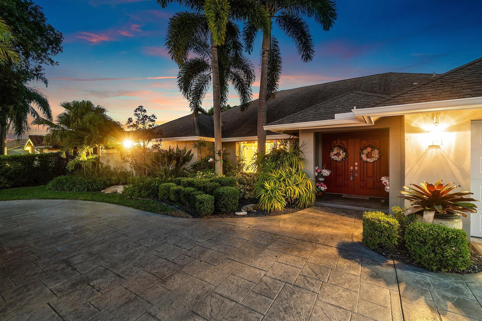A single-story house with a stamped concrete driveway, palm trees, and double front doors — 2063 Amesbury Circle, Wellington FL 33414, WELLINGTON, FL