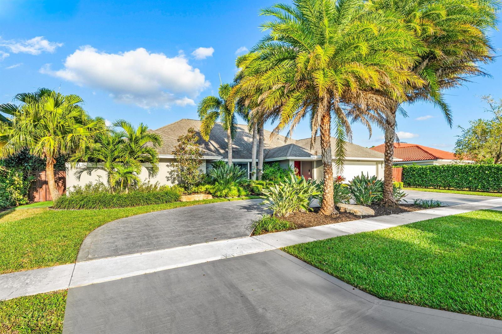 A single-story house with a curved driveway, palm trees, and a landscaped front yard — 2063 Amesbury Circle, Wellington FL 33414, WELLINGTON, FL