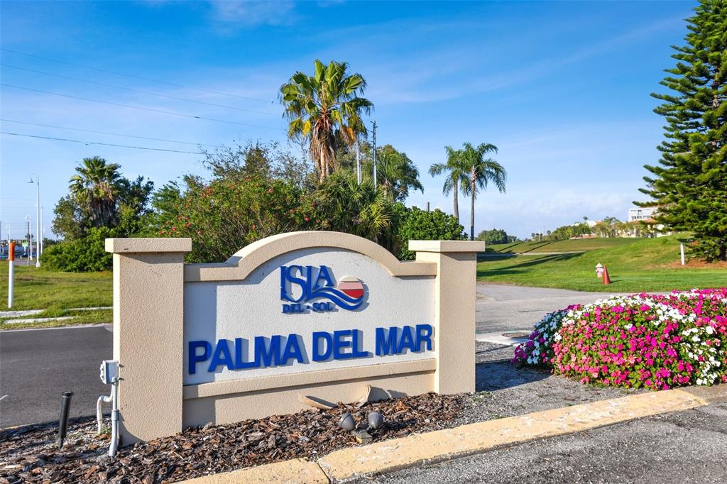 A beige monument sign for Palma Del Mar stands near a road and landscaping — 6105 PALMA DEL MAR BOULEVARD S UNIT 120, ST PETERSBURG, FL