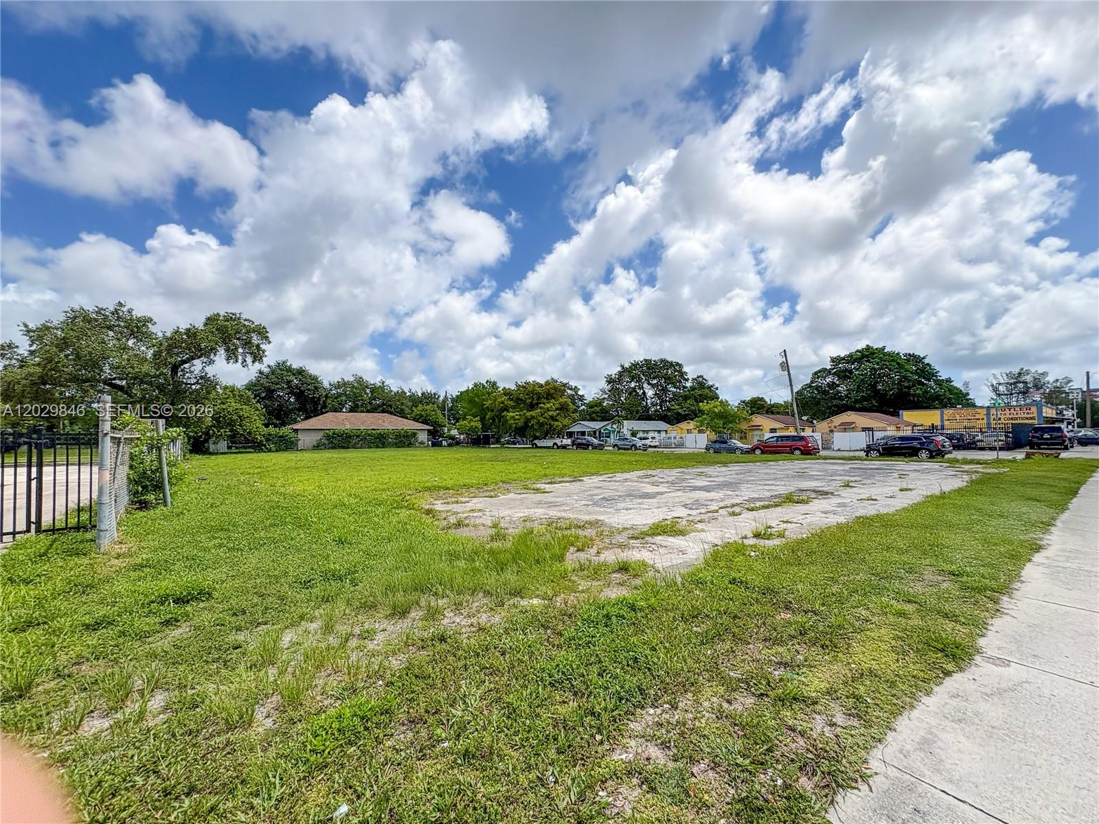 A vacant grassy lot features a concrete slab foundation under a cloudy blue sky — 7920 NW 11th Ave, Miami FL 33150, MIAMI, FL