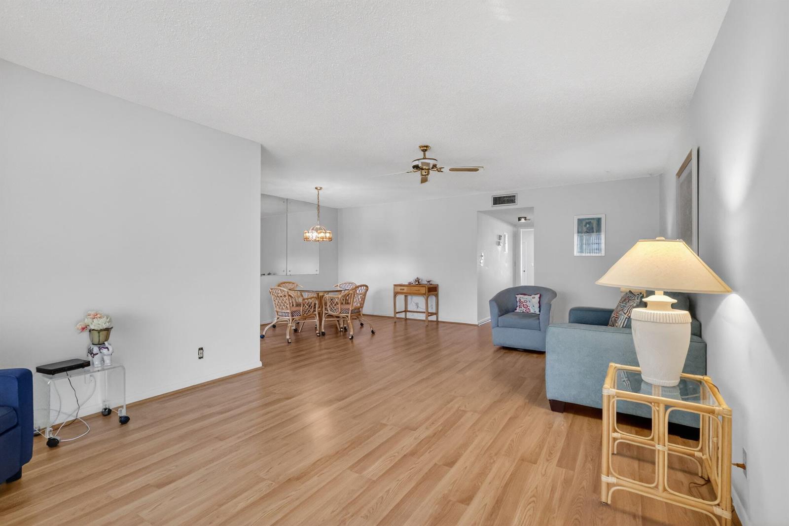 A living and dining area with light wood-look flooring, white walls, and a ceiling fan — 5091 Lakefront Boulevard # C, Delray Beach FL 33484, DELRAY BEACH, FL