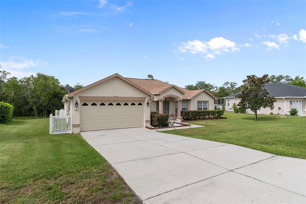 A single-story house with a beige stucco exterior, a two-car garage, and a concrete driveway — 7 BIGLEAF COURT, HOMOSASSA, FL
