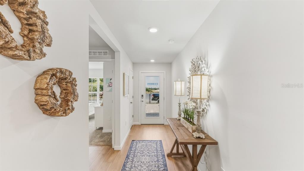 A bright entryway features wood-look flooring, a console table, and wall-mounted decorative art — 9620 TURTLE GRASS CIRCLE, PUNTA GORDA, FL