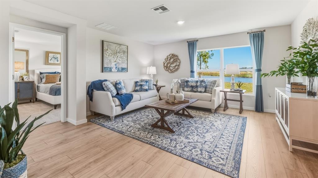 A living room with light wood floors, a blue patterned rug, and a view of water — 9620 TURTLE GRASS CIRCLE, PUNTA GORDA, FL
