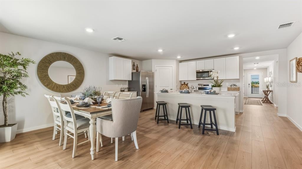 An open-concept kitchen and dining area features white cabinetry, a kitchen island, and wood flooring — 9620 TURTLE GRASS CIRCLE, PUNTA GORDA, FL