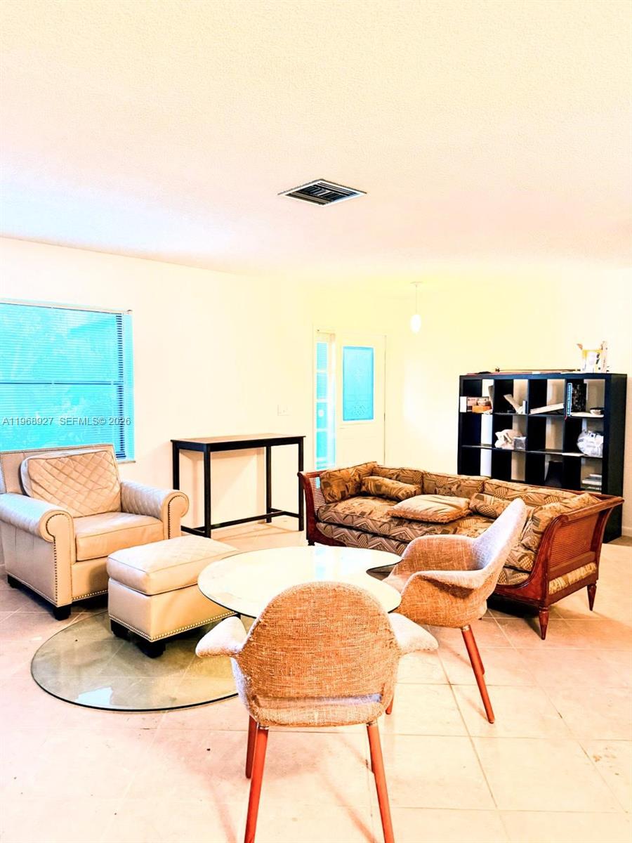 This living room features tile flooring, a beige armchair with ottoman, and a patterned sofa — 766 NW 24th Ave, Delray Beach FL 33445, DELRAY BEACH, FL
