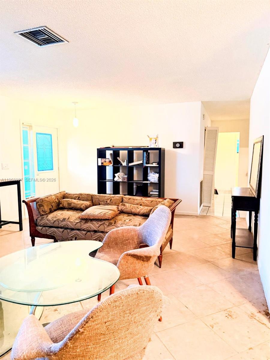 A living room features a patterned sofa, a glass table, and a black shelving unit — 766 NW 24th Ave, Delray Beach FL 33445, DELRAY BEACH, FL