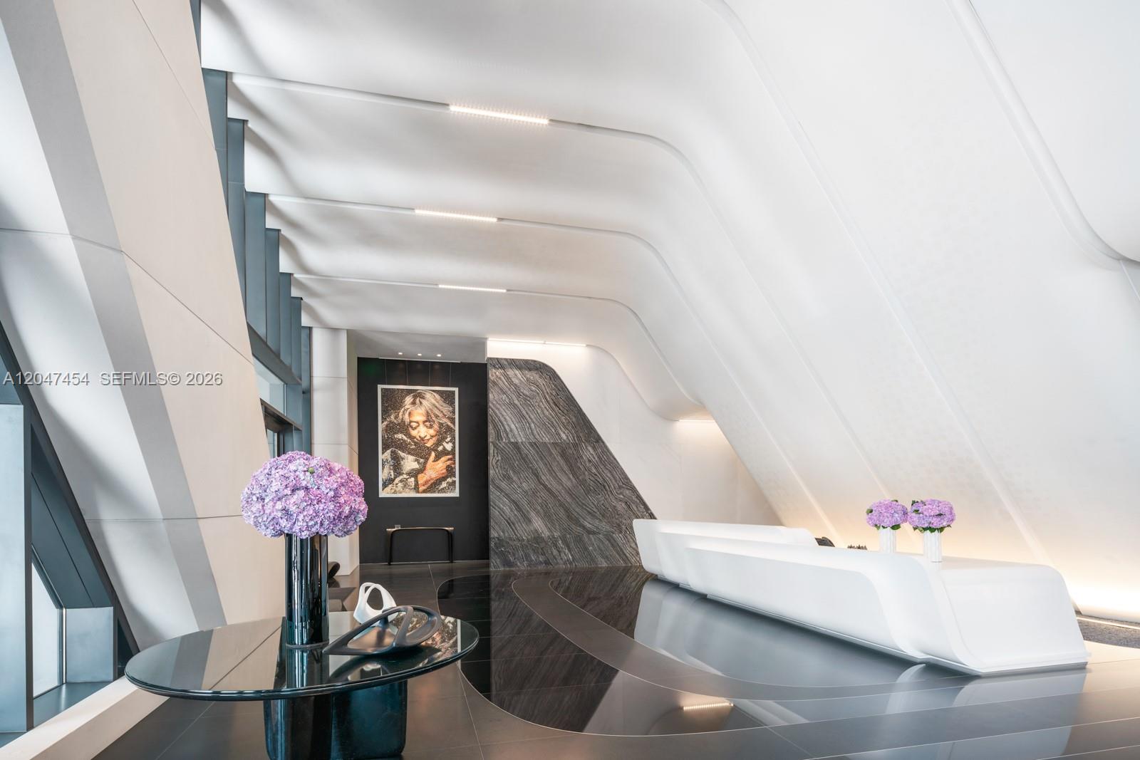 A modern lobby features a white reception desk, dark marble flooring, and a large portrait — 1000 Biscayne Blvd # 4401, Miami FL 33132, MIAMI, FL