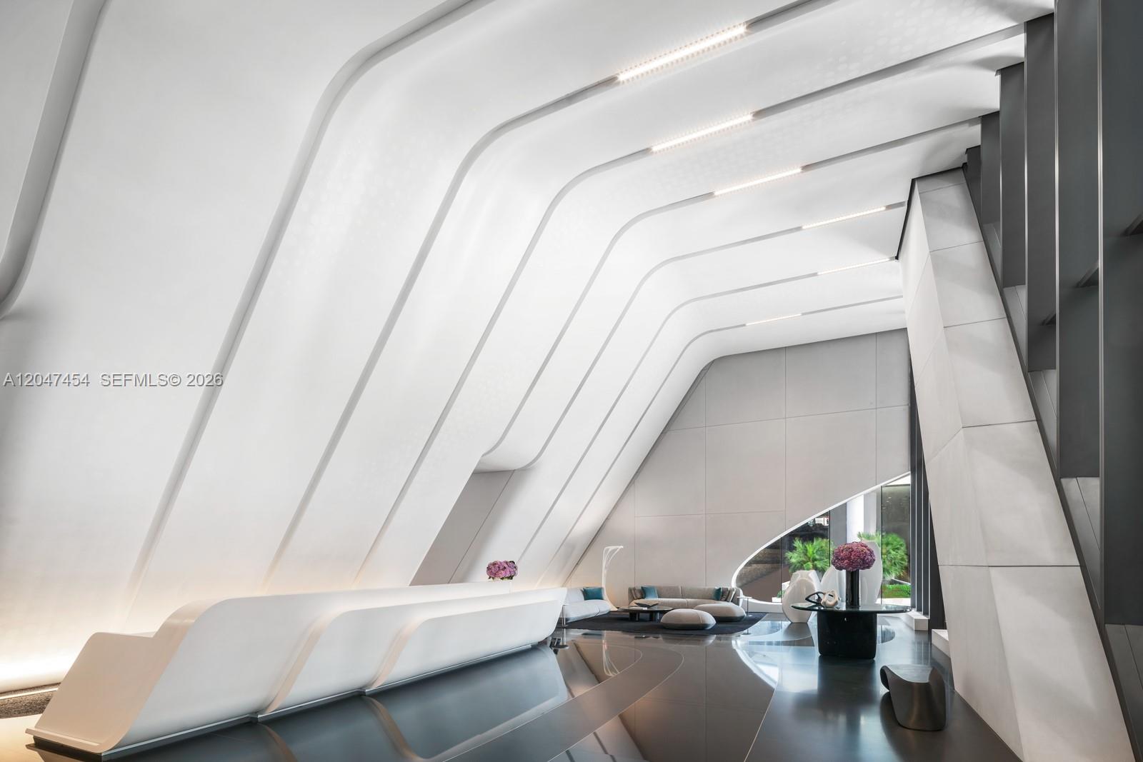 A modern lobby features a white curved reception desk, angled ceiling panels, and dark flooring — 1000 Biscayne Blvd # 4401, Miami FL 33132, MIAMI, FL
