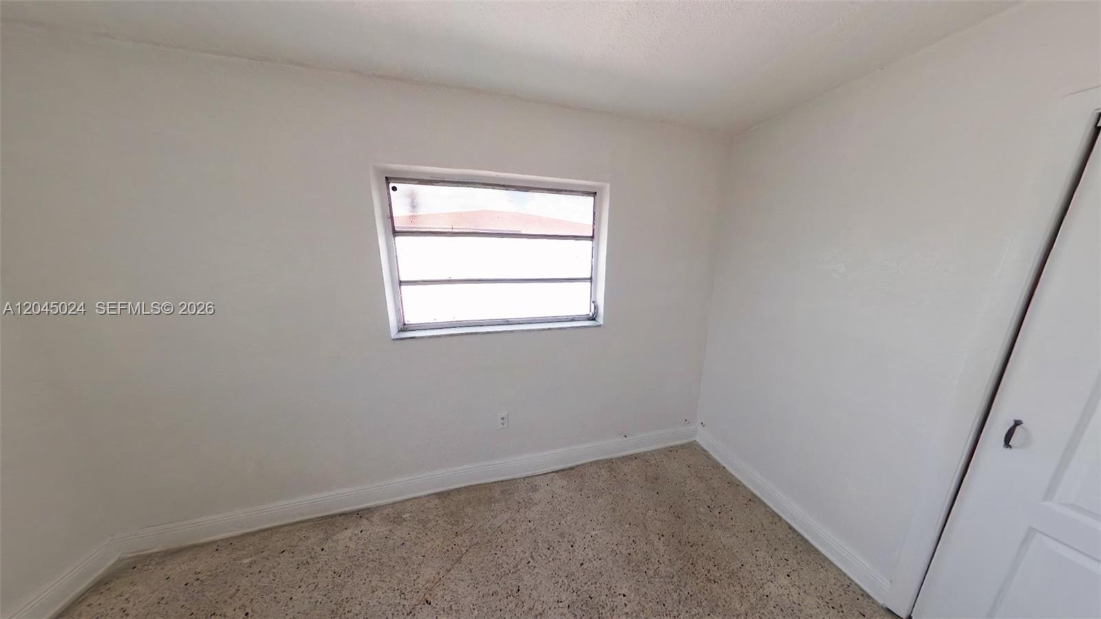 An empty room features white walls, a horizontal window, and a speckled tile floor — 2712 W 10th Ave # 5, Hialeah FL 33010, HIALEAH, FL