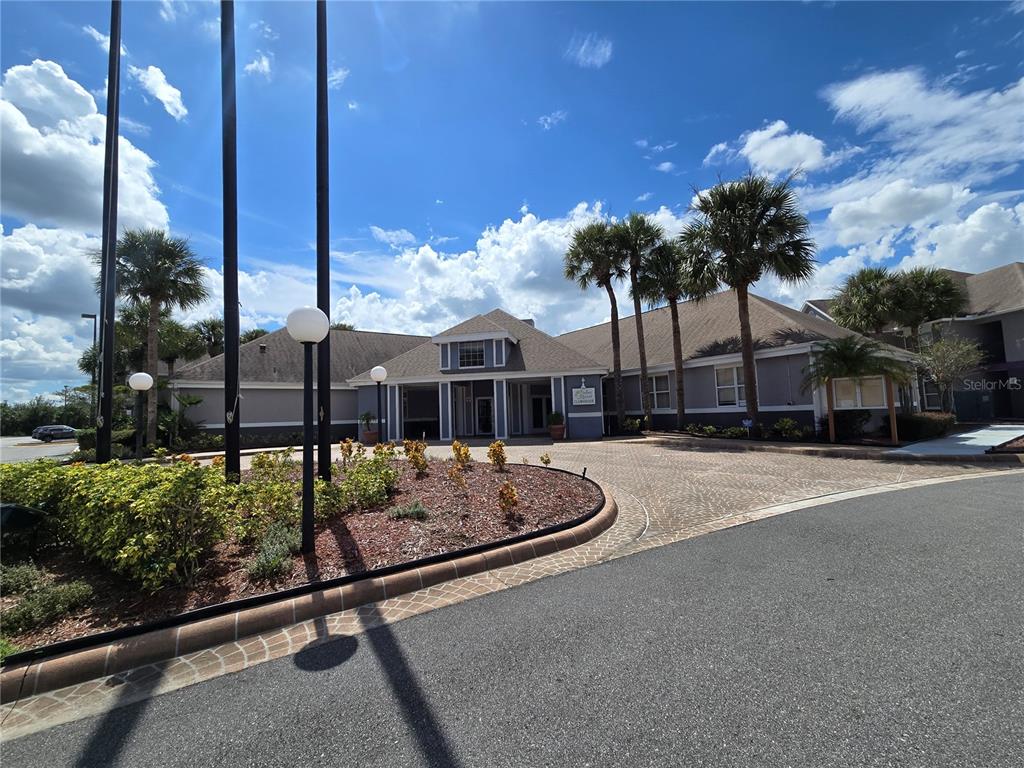 The exterior of a clubhouse building features a paved circular driveway and palm trees — 3100 PARKWAY BOULEVARD UNIT 752, KISSIMMEE, FL