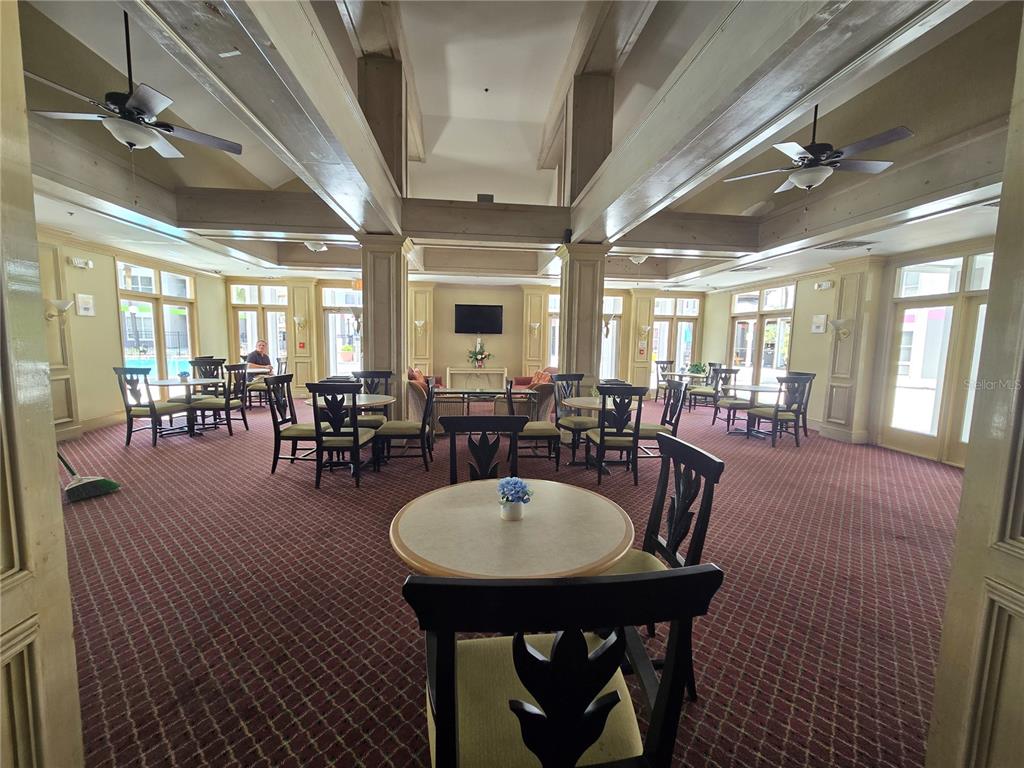 A spacious community room features multiple dining tables, ceiling fans, and large windows — 3100 PARKWAY BOULEVARD UNIT 752, KISSIMMEE, FL