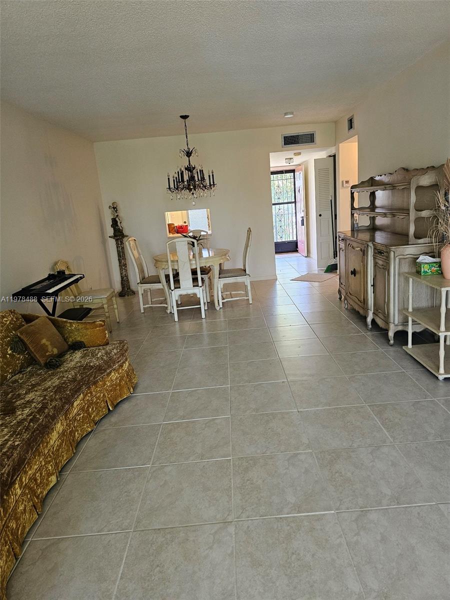 A living and dining area features tile flooring, a chandelier, and a vintage hutch — 1103 NW 58th Ter # 321, Sunrise FL 33313, SUNRISE, FL