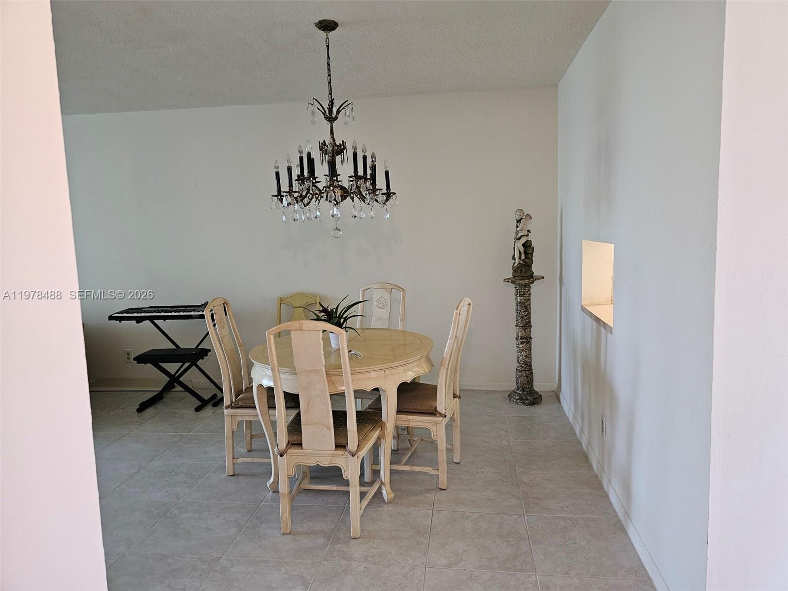 A dining room features a round table, four chairs, a chandelier, and a decorative pedestal — 1103 NW 58th Ter # 321, Sunrise FL 33313, SUNRISE, FL