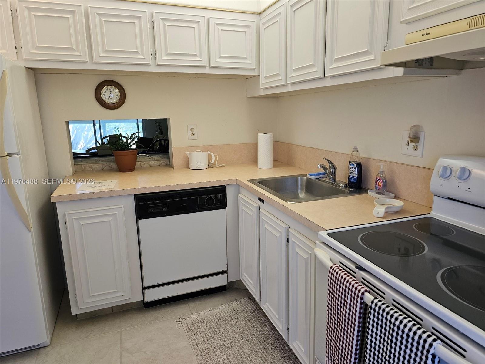 A kitchen features white cabinets, a black dishwasher, a stainless steel sink, and a stove — 1103 NW 58th Ter # 321, Sunrise FL 33313, SUNRISE, FL