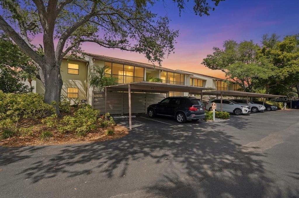 A multi-story apartment building with covered parking spaces and a paved driveway in front — 646 BIRD BAY DRIVE E UNIT 205, VENICE, FL
