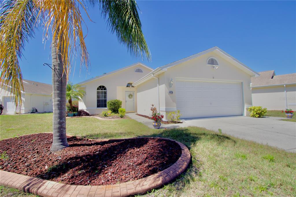 A single-story house with a white garage, light-colored stucco exterior, and a palm tree — 4429 WHITTON WAY, NEW PORT RICHEY, FL