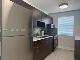A kitchen features dark wood cabinets, stainless steel appliances, and a window with white blinds — 1607 NW 16th Ave # 1, Miami FL 33125, MIAMI, FL