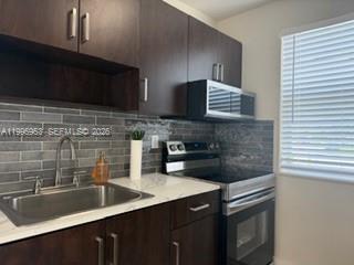 A kitchen features dark wood cabinets, stainless steel appliances, a gray tiled backsplash, and countertops — 1607 NW 16th Ave # 1, Miami FL 33125, MIAMI, FL